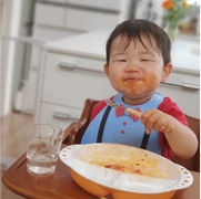 料理を口の周りにつけながら食べている子どもの写真